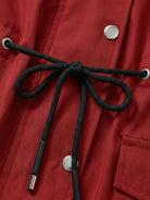 Close-up of black adjustable drawstring on red water resistant hooded striped windbreaker jacket