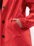 Water-resistant oversized hooded windbreaker rain jacket in light blue with pockets and adjustable waist.