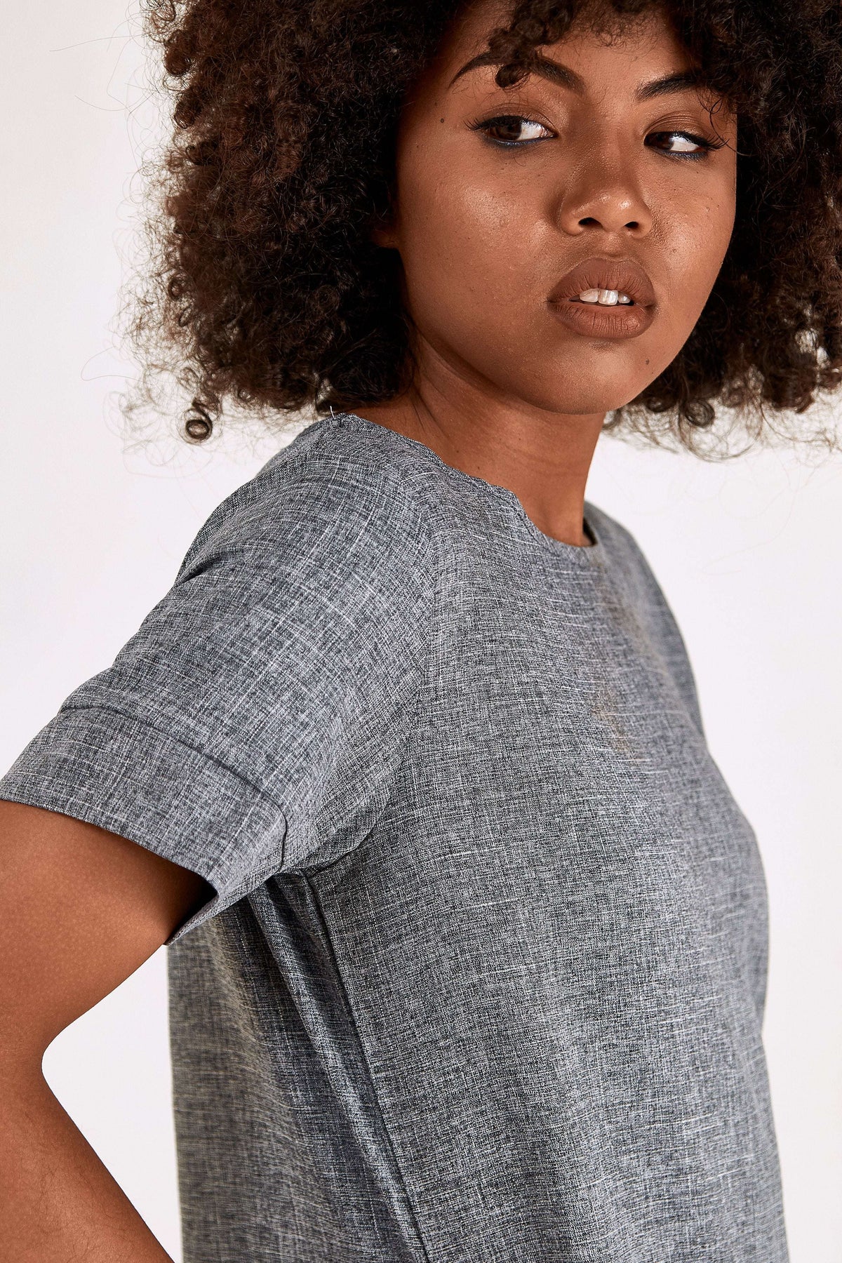 Woman wearing grey short sleeve shift dress with round neck and side pockets